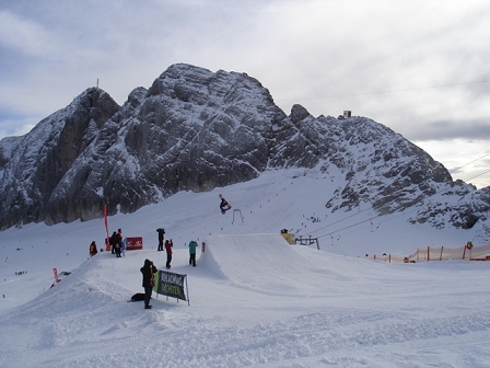 Snowboarder macht einen Backflip über eine Schanze.